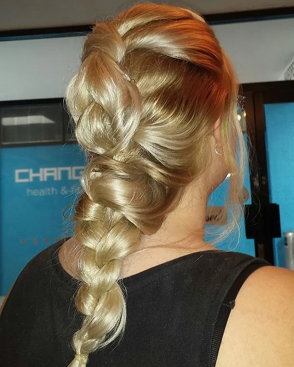 The back view of a person with blonde hair styled in an intricate braid, against a backdrop of what appears to be a commercial or health-related establishment